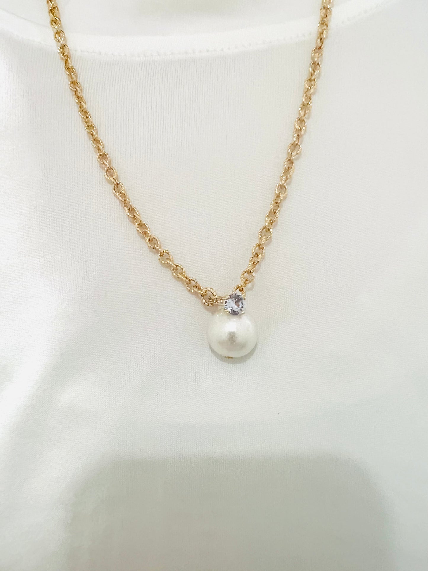 Glittering golden necklace with hanging pearl