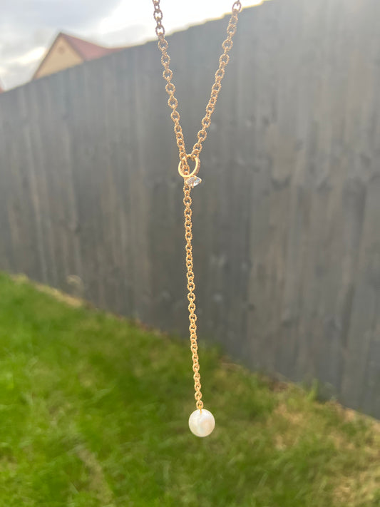 Glittering golden necklace with hanging pearl